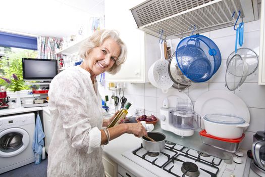 Portrait of happy senior woman preparing food in domestic kitchen