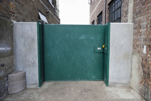 Closed green gate connected to buildings