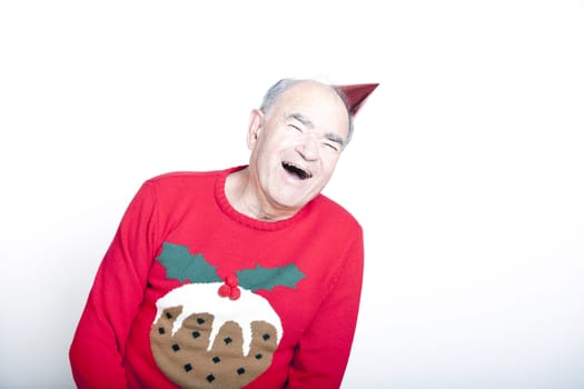 Senior adult man wearing a Christmas jumper and a red party hat