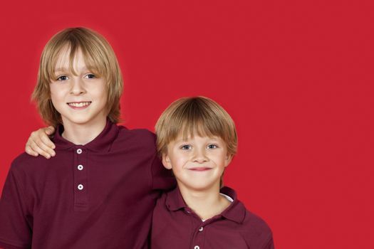 Portrait of two happy brothers against red background