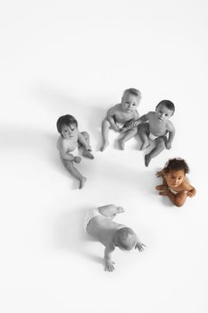 High angle view of baby girl looking up with other babies sitting on floor
