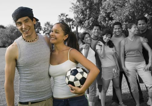Happy couple holding soccer ball enjoying with friends at park