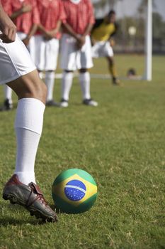 Soccer players preparing for a free kick in front of Brazilian flag