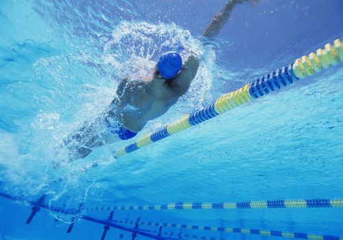 Young professional male athlete doing backstroke in swimming pool