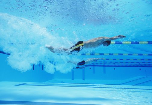 Underwater shot of three male athletes racing in swimming pool
