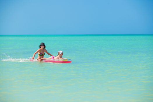 Mother with young daughter on an air mattress in the sea