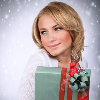 Portrait of sensual blonde girl holding stylish wrapped gift box, Christmas time party, New Year surprise, happiness and enjoyment concept
