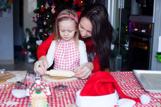 Little girl with beautiful mother baking Christmas gingerbread cookies together