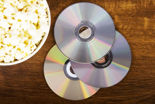 Picture of popcorn in a bowl and CDs lying on table.