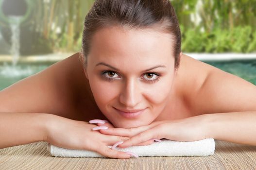 Young woman lying in a spa ready to get a massage in a green background