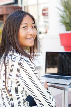 Smiling young asian girl working on her laptop
