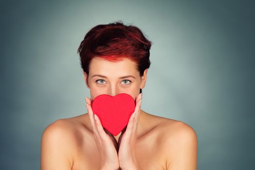 woman holding red heart in front of her face