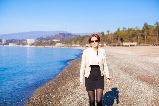 Beautiful young woman walking on the beach in winter sunny day alone