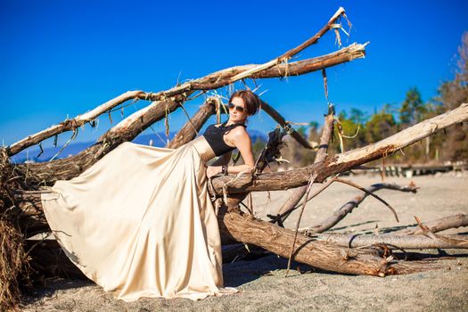 Charming young woman in a long beautiful dress posing on the beach