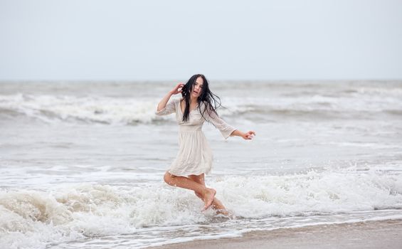 Beautiful young woman in the cold sea waves