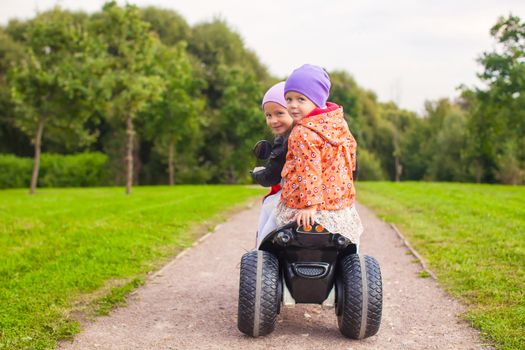 Portrait of adorable little girls ride a motorbike in green park