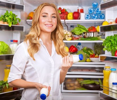 Woman chosen yogurt in opened refrigerator