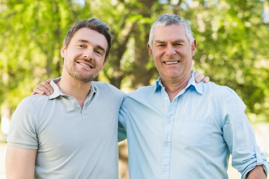 Smiling father with adult son at park