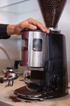 Barista using coffee grinder to grind beans