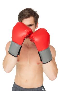 Muscly man wearing red boxing gloves in guard position