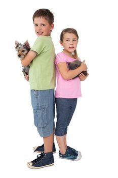 Siblings holding their pets and smiling at camera on white background