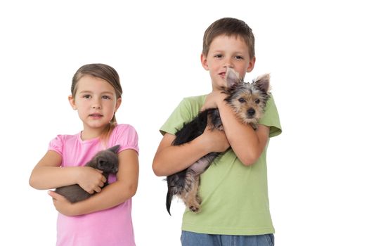 Cute siblings holding their pets and smiling at camera on white background