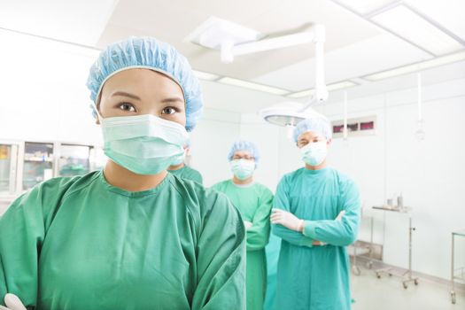 Smiling surgeon posing with a team in a surgical room