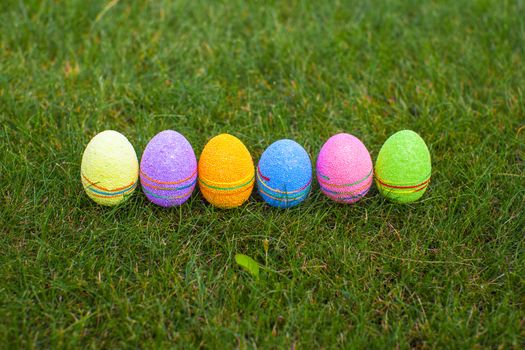 Multi-colored Easter eggs on green grass