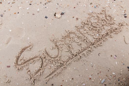 The word summer  handwritten in sand 
