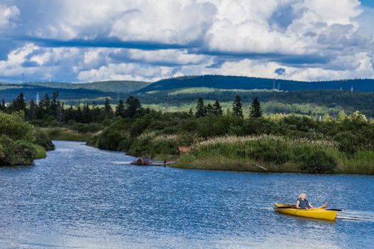 Calm River and Woman relaxing in a Yellow Kayak