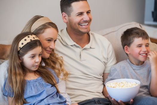Cheerful family watching tv on sofa in living room