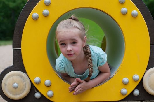 Young girl sitting in crawl tube on the playground
