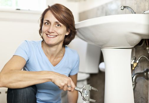 Confident woman repairing sink in bathroom at home