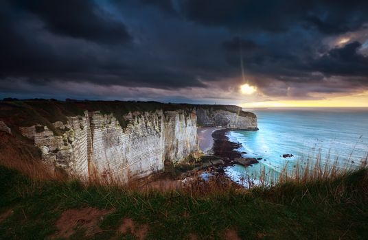 sunshine and storm sky over cliffs in ocean