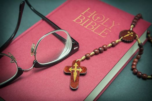 Glasses adjusted on the holy bible and beads