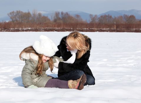 Young mother and her little daughter enjoying beautiful winter day outdoors