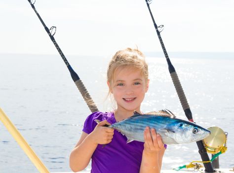 Blond girl fishing bonito Sarda tuna trolling in sea