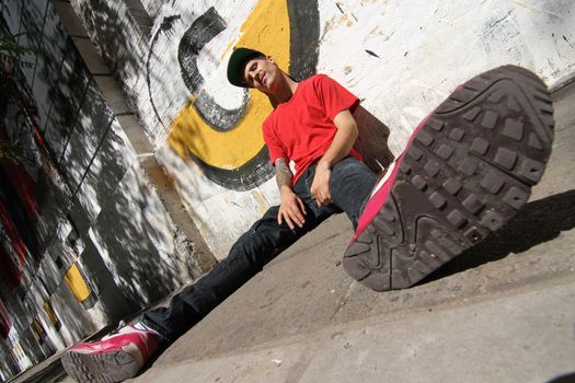 A Rapper leaning against a Graffiti wall.