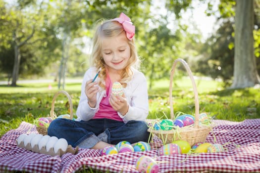 Cute Young Girl Happily Coloring Her Easter Eggs with Paint Brush in the Park.
