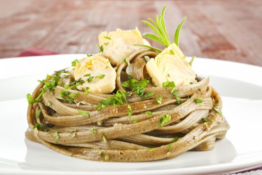 Pasta with artichoke and fresh herbs close up.