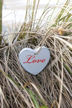 inscribed blue wooden heart on beach dunes