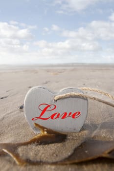 inscribed wooden love heart in the sand on a wild Atlantic way Irish beach in summer with copy space