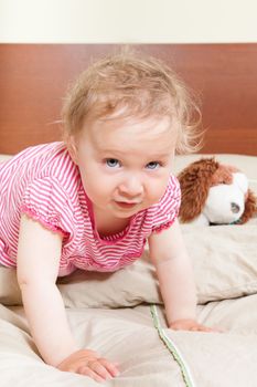 Cute baby girl looking into camera on bed.