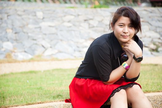 Asian women black shirt. Sitting on grass in park areas.