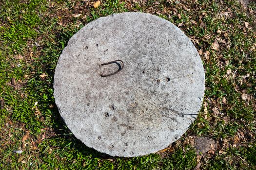 Concrete manhole cover in the grass