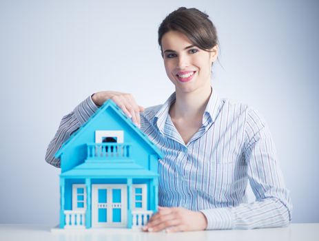 Beautiful woman at desk with light blue model house.