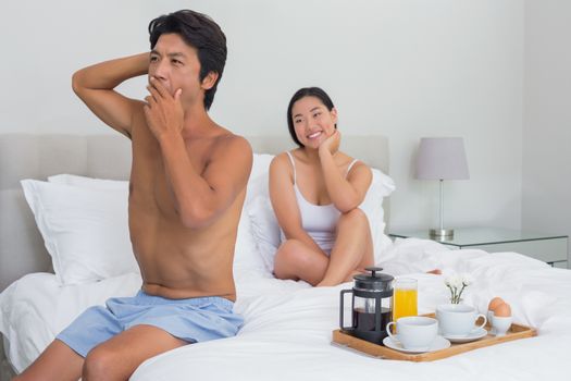 Smiling woman watching her boyfriend yawn and stretch