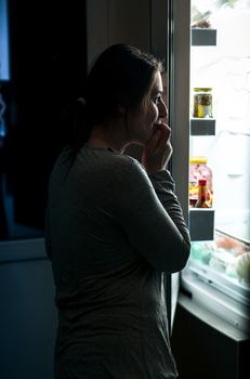 woman in pajamas opening refrigerator at night