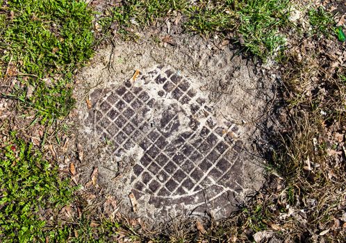 Manhole with metal cover sunk into the ground and grass