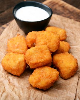 Chicken nuggets with garlic sauce on old wooden background